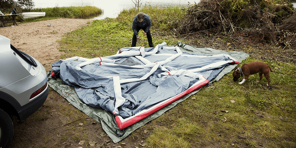 Manu Tuppurainen levittää Audi-telttaa Hiidenveden rannalla Papu-koiran seuraillessa vierellä toimintaa.